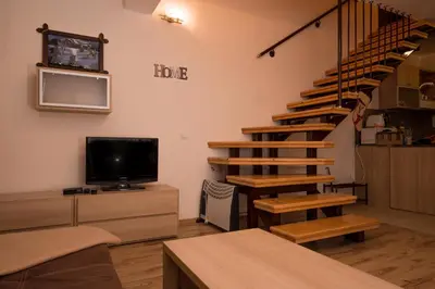a living room with a spiral staircase and a tv at Borovets Gardens Aparthotel Seasons Borovets PM in Borovets