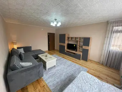a living room with a gray couch and a tv at Апартамент Котеви in Sandanski