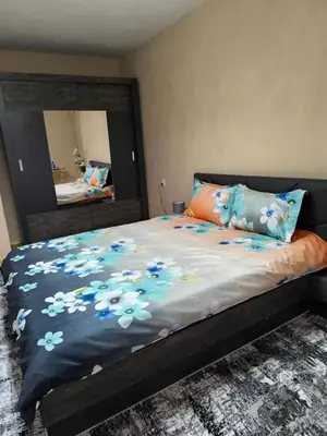 a bed with a blue blanket with flowers on it at Апартамент Котеви in Sandanski