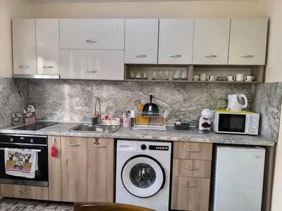 a kitchen with a washing machine and a microwave at Апартамент Котеви in Sandanski