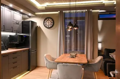 a kitchen and dining room with a table and a clock at All Seasons Apartment in Sofia