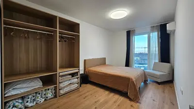 a bedroom with a bed and a chair and a window at Cozy Urban Heaven with Dedicated Parking Spot in Sofia