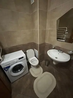 a bathroom with a toilet a sink and a washing machine at ИН Хоум Комфорт in Borovets