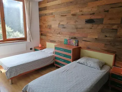a bedroom with two beds and a wooden wall at ИН Хоум Комфорт in Borovets