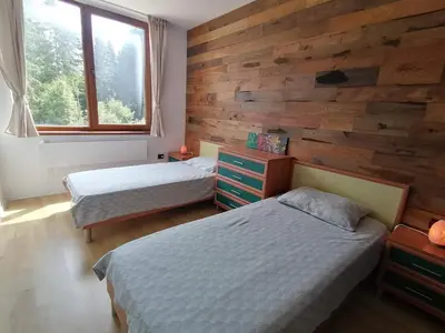 a bedroom with two beds and a wooden wall at ИН Хоум Комфорт in Borovets