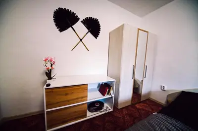 a bedroom with a dresser with a clock on the wall at Апартамент Япония in Blagoevgrad