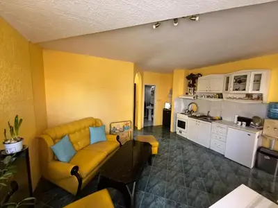 a living room with a yellow couch and a kitchen at Apartment Tinka in Sofia