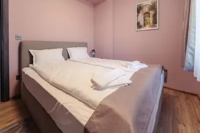 a bedroom with a bed with white sheets and books on it at Rila Family Haven in Samokov