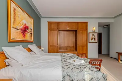 a bedroom with a large white bed with a table at Къща за гости Карлък in Smolyan