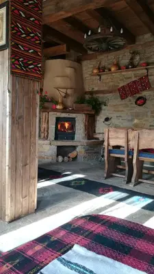 a room with a fireplace and a table and a stove at Spa&Relax Скендерова Къща in Leshten