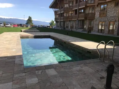 a swimming pool in front of a building at Pirin Golf View Apartment Bansko in Bansko