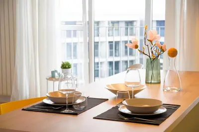 a table with two plates and glasses and a vase with flowers at Scandinavian Airy APT in Business Area & Airport in Sofia