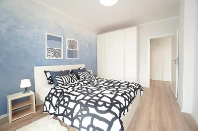 a bedroom with a black and white bed and blue walls at Scandinavian Airy APT in Business Area & Airport in Sofia