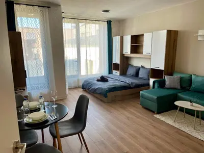 a bedroom with a bed and a couch and a table at Comfort Airport Metro Suite in Sofia