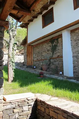 a house with a stone wall next to a yard at Вили Панорама Лещен in Leshten