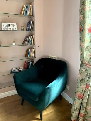 a green chair in a room with a book shelf at Cozy townhouse in the heart of Sofia in Sofia
