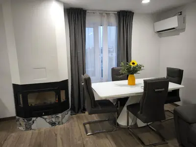 a living room with a fireplace and a table and chairs at Victoria Elegance Apartment in Sofia