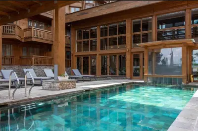 a swimming pool with chairs and a building at Pirin Golf Resort & SPA Two-Bedroom Apartment in Razlog