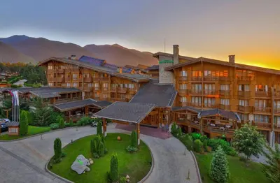 a resort with a large building with mountains in the background at Pirin Golf Resort & SPA Two-Bedroom Apartment in Razlog