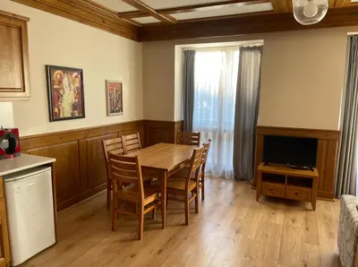 a dining room with a table and chairs and a television at Pirin Golf Resort & SPA Two-Bedroom Apartment in Razlog