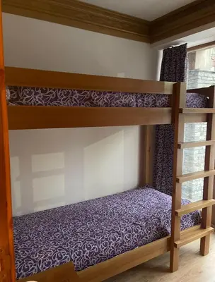 a bedroom with two bunk beds with purple sheets at Pirin Golf Resort & SPA Two-Bedroom Apartment in Razlog