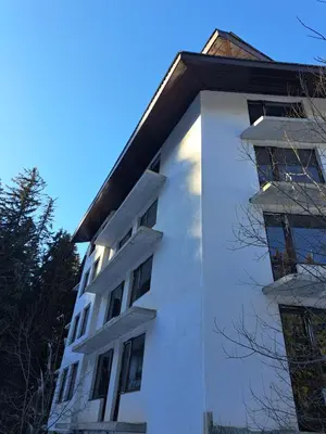 a white building with windows on the side of it at ВасиленаАпарт in Pamporovo