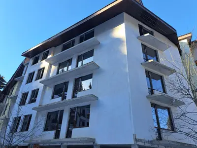a white building with windows on the side of it at ВасиленаАпарт in Pamporovo