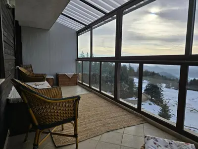 a room with a table and chairs and large windows at Pampo-Heaven in Smolyan