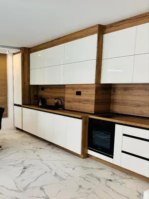 a kitchen with white cabinets and a marble floor at luxuri suite ''dezodava'' in Sandanski