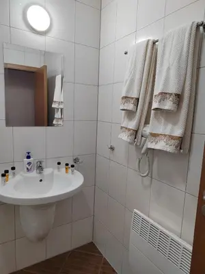 a white bathroom with a sink and a mirror at Mountain Ski & SPA apartment in Pamporovo