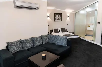 a living room with a black couch and a table at Семеен Хотел Олимп in Sopot
