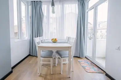 a white table and chairs in a room with windows at Top Center in Blagoevgrad