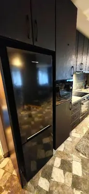 a kitchen with a large black refrigerator in a kitchen at Modern apartment with terrace in Chepelare