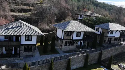a group of houses on a stone wall at Трите къщи in Leshten