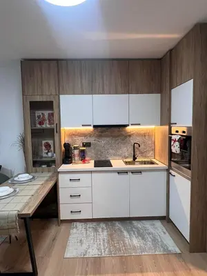 a kitchen with white cabinets and a wooden table at Millennium apartment in Bansko
