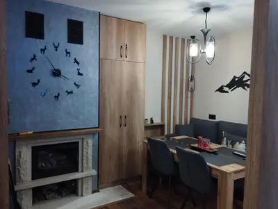 a dining room with a table and a clock over a fireplace at студио Е 13 in Pamporovo