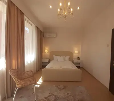 a bedroom with a white bed and a chandelier at Princess Apartment in Sandanski