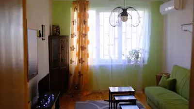 a living room with a green couch and a window at просторен и уютен двустаен в Долен Лозенец - кварталът на артистите in Sofia