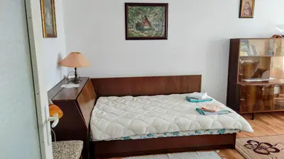 a bedroom with a bed and a dresser with a lamp at Апартамент Калоян in Banya