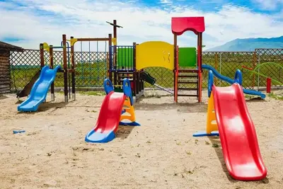 a playground with colorful playground equipment in the sand at Стилни и Луксозни Вили за разпускане in Malo Buchino