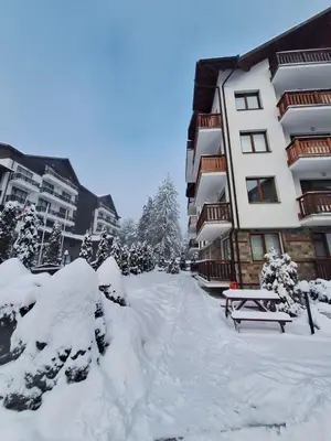 a snow covered street in front of a building at Rila Park by the Slopes in Borovets