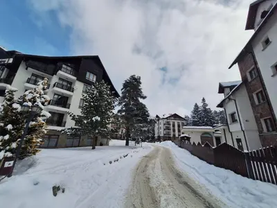 a snow covered street in front of a building at Rila Park ap by the Slopes in Borovets
