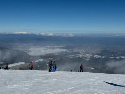 a group of people standing on top of a snow covered slope at Rila Park ap by the Slopes in Borovets