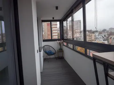 a hallway with large windows and a blue chair at Blue Iris, 2BR, Stunning Views, Jacuzzi and Workspace in Sofia