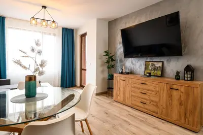 a living room with a table and a television on a wall at DreamAparts in Velingrad