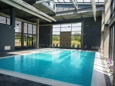 a large swimming pool with blue water in a building at Харизма in Hisarya
