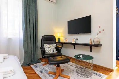 a black chair sitting in a living room with a tv at HeBrOs Park Apartment Next to Kapana 2BR in Plovdiv