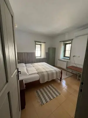a bedroom with a bed and two windows at Apаrtment Melnik home in Melnik