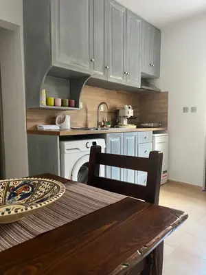 a kitchen with white cabinets and a table and a sink at Apаrtment Melnik home in Melnik