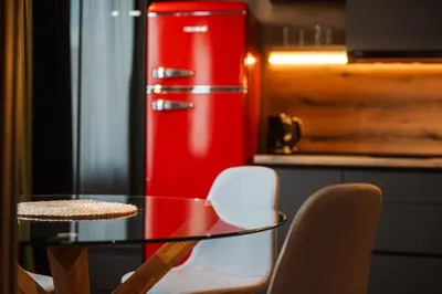 a glass table with chairs and a red refrigerator at Уютно студио Verde Suites 14 in Blagoevgrad